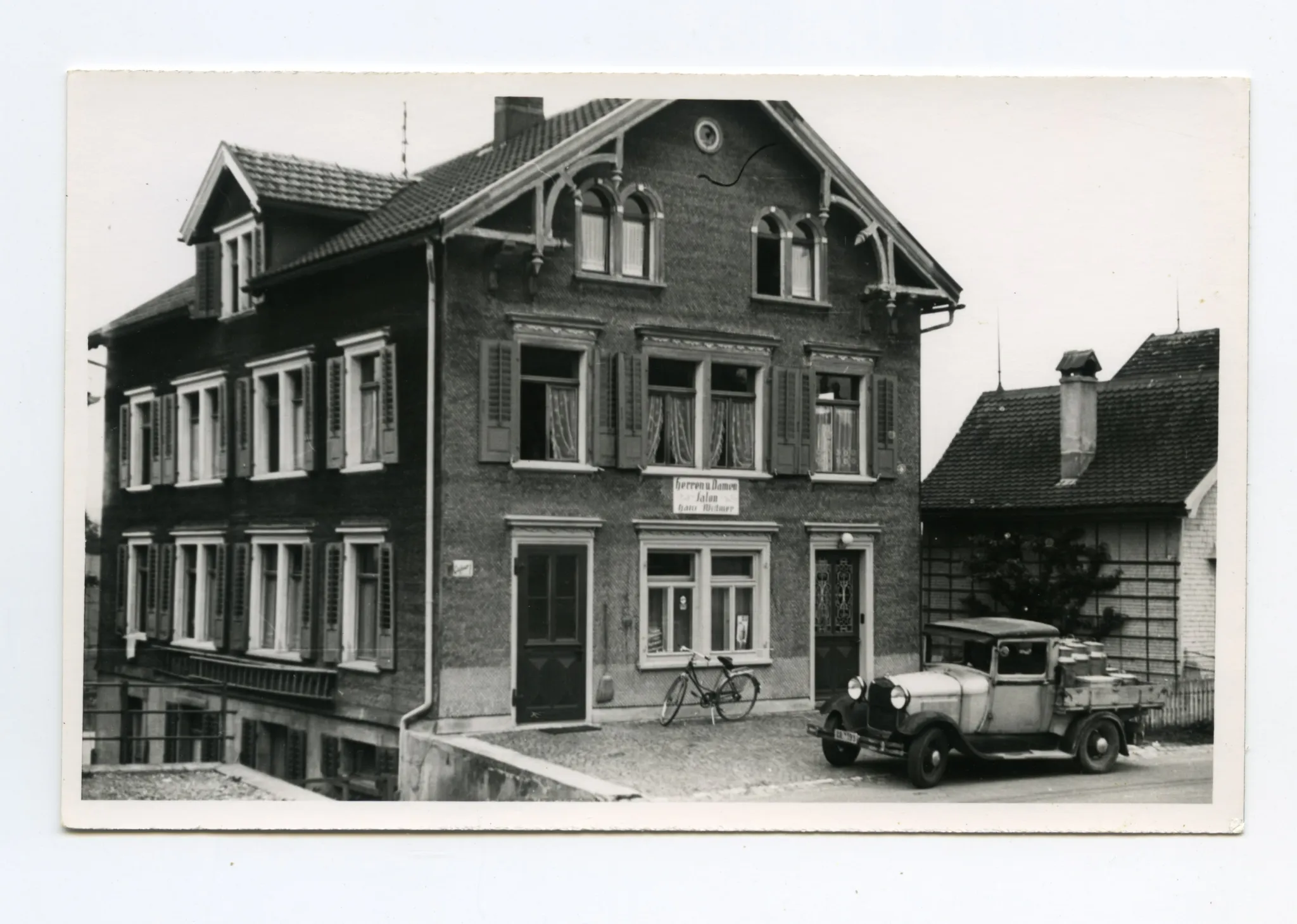 Gebäudeansicht mit Velo und Milchwagen vor dem Haus, Karten identisch