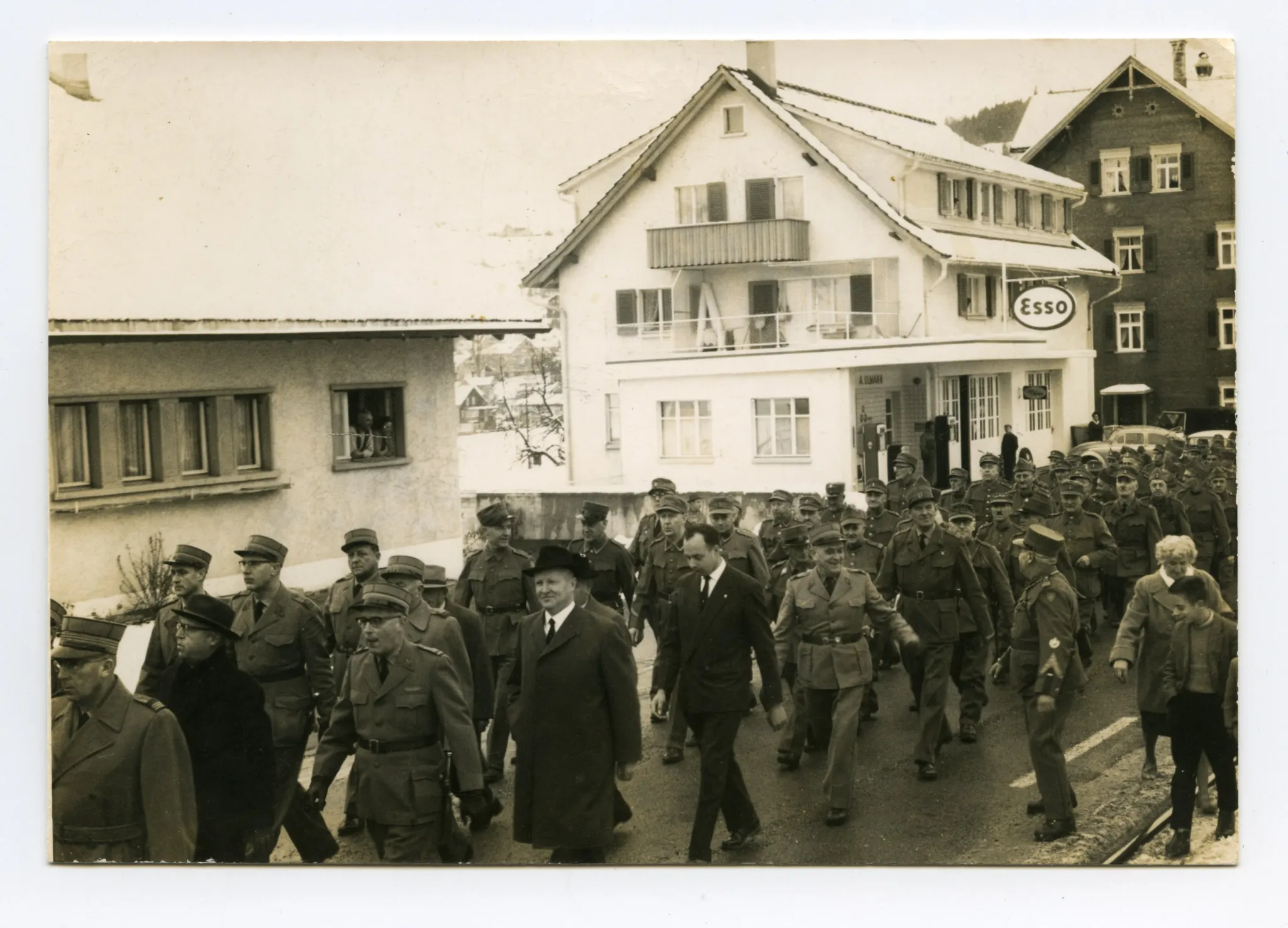 Wehrmänner marschieren auf der Strasse (Ebni) Richtung Zeughaus, Im Hintergrund Tankstelle