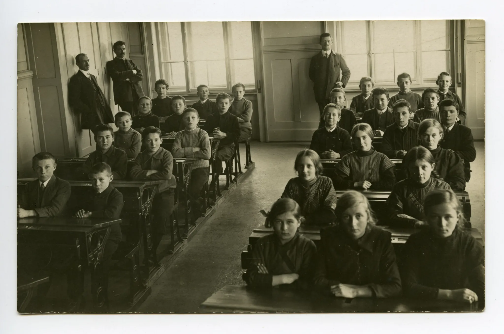 drei Lehrer mit Schülern und Schülerinnen sitzend in den Bänken (vgl. 01-04, gleiche Lehrer, aber andere Schulklasse, dat. 1913)