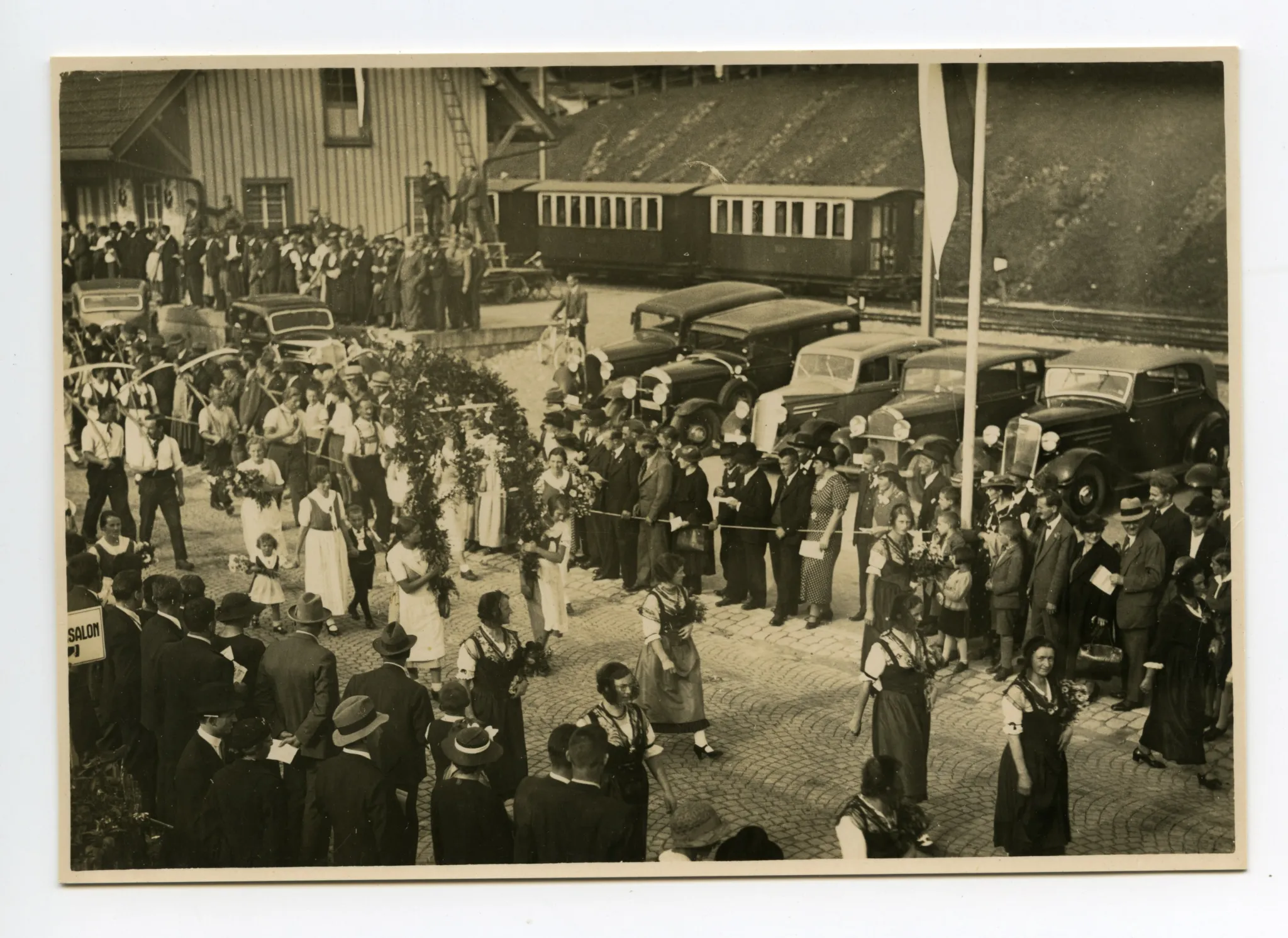 Gruppe der Bauern und Bäuerinnen vor dem Güterschuppen, vorauslaufend Trachtengruppe (vgl. Ho.30-038)