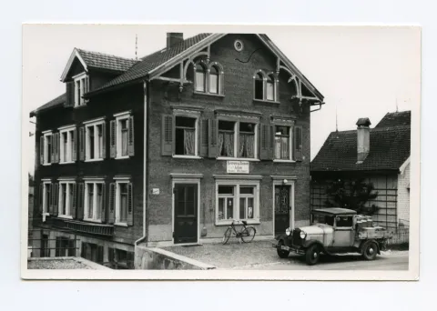 Gebäudeansicht mit Velo und Milchwagen vor dem Haus, Karten identisch