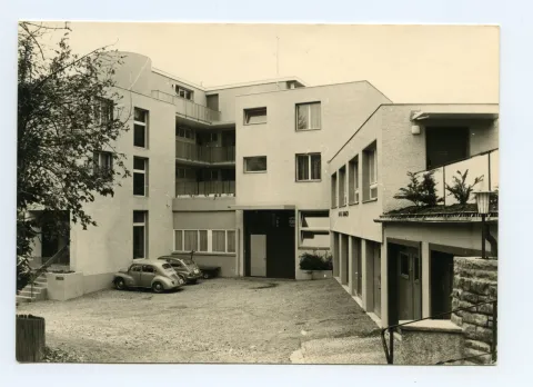 Karte 1: Firmenkomplex mit Eingangsbereich und parkenden Autos; Karte 2: Rückansicht des Firmengebäudes (Mietwohnungen mit Balkon)