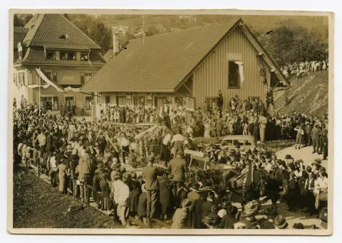 Fuhrwerk der Zimmerei mit arbeitenden Zimmerleuten auf dem Wagen, im Hintergrund Güterschuppen und Bahnhof