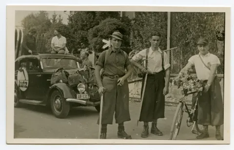 Gruppe des Sportgeschäfts „Lutz“, Nahaufnahme Gruppenbild mit zwei Wanderern und einem Velofahrer, im Hintergrund dekorierter Wagen